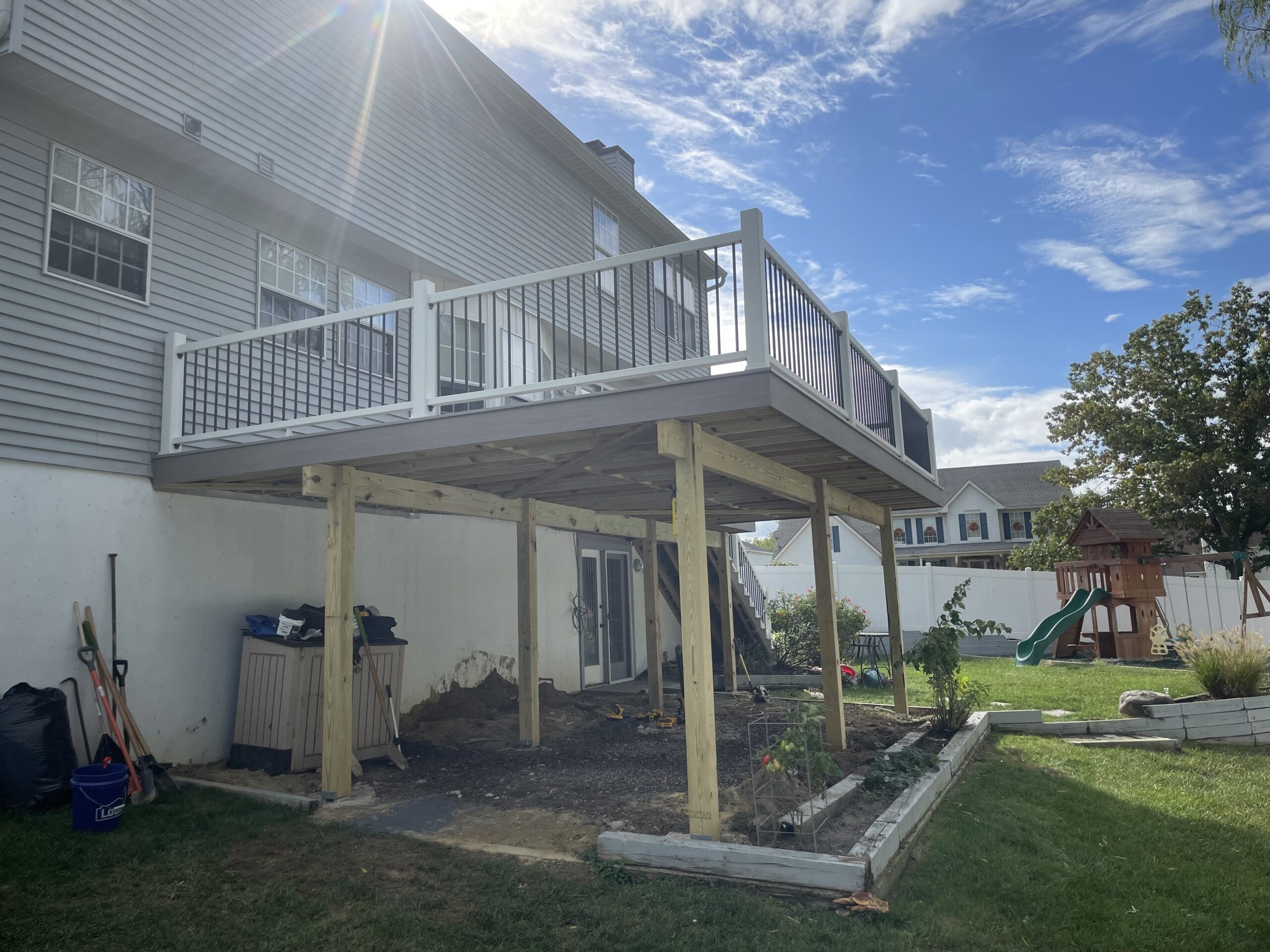 A back yard with a deck and a garbage can